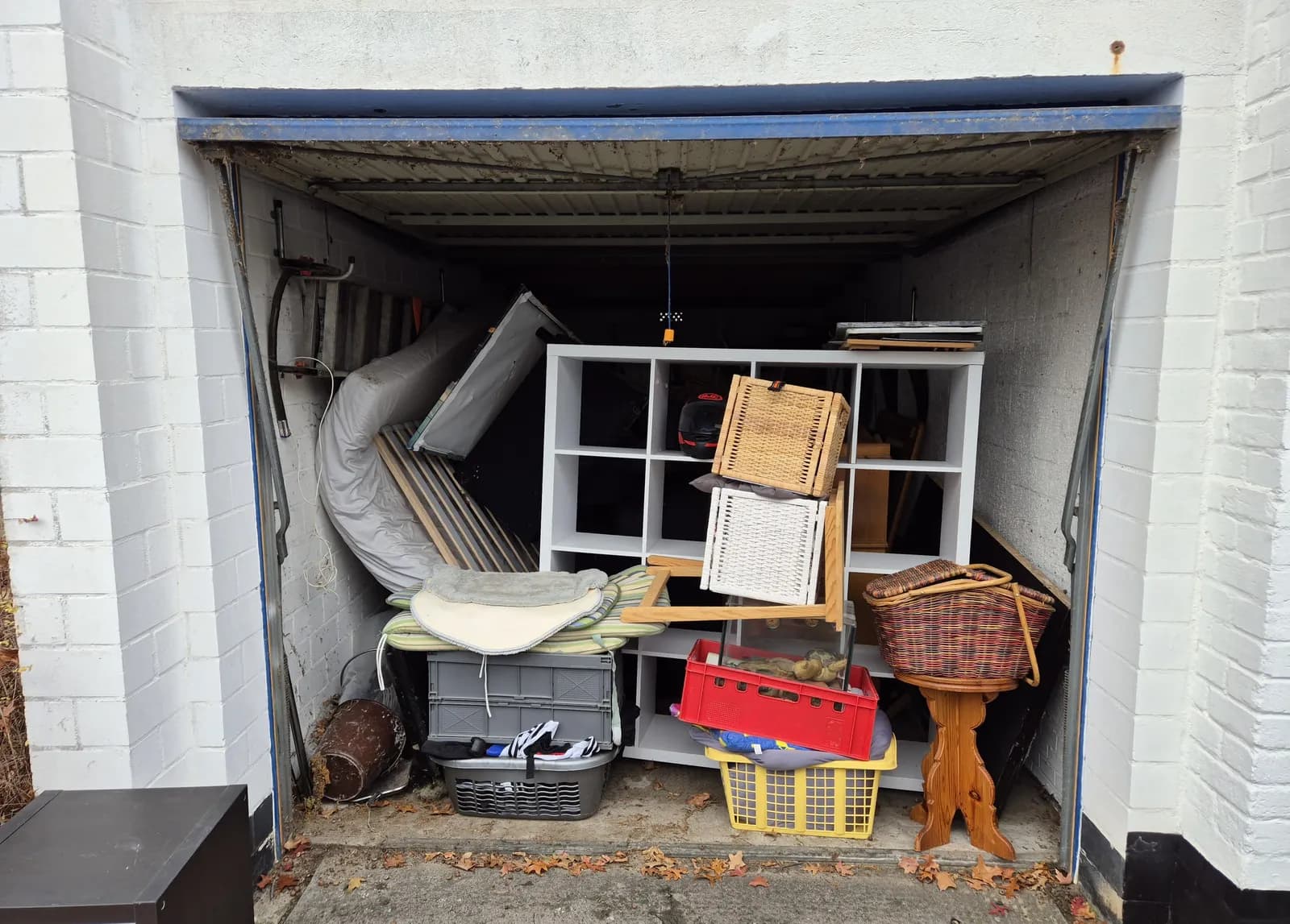 Vollgestellte Garage in Berlin mit Regal, Kisten, Körben und einer Sonnenliege, bereit zur Entrümpelung