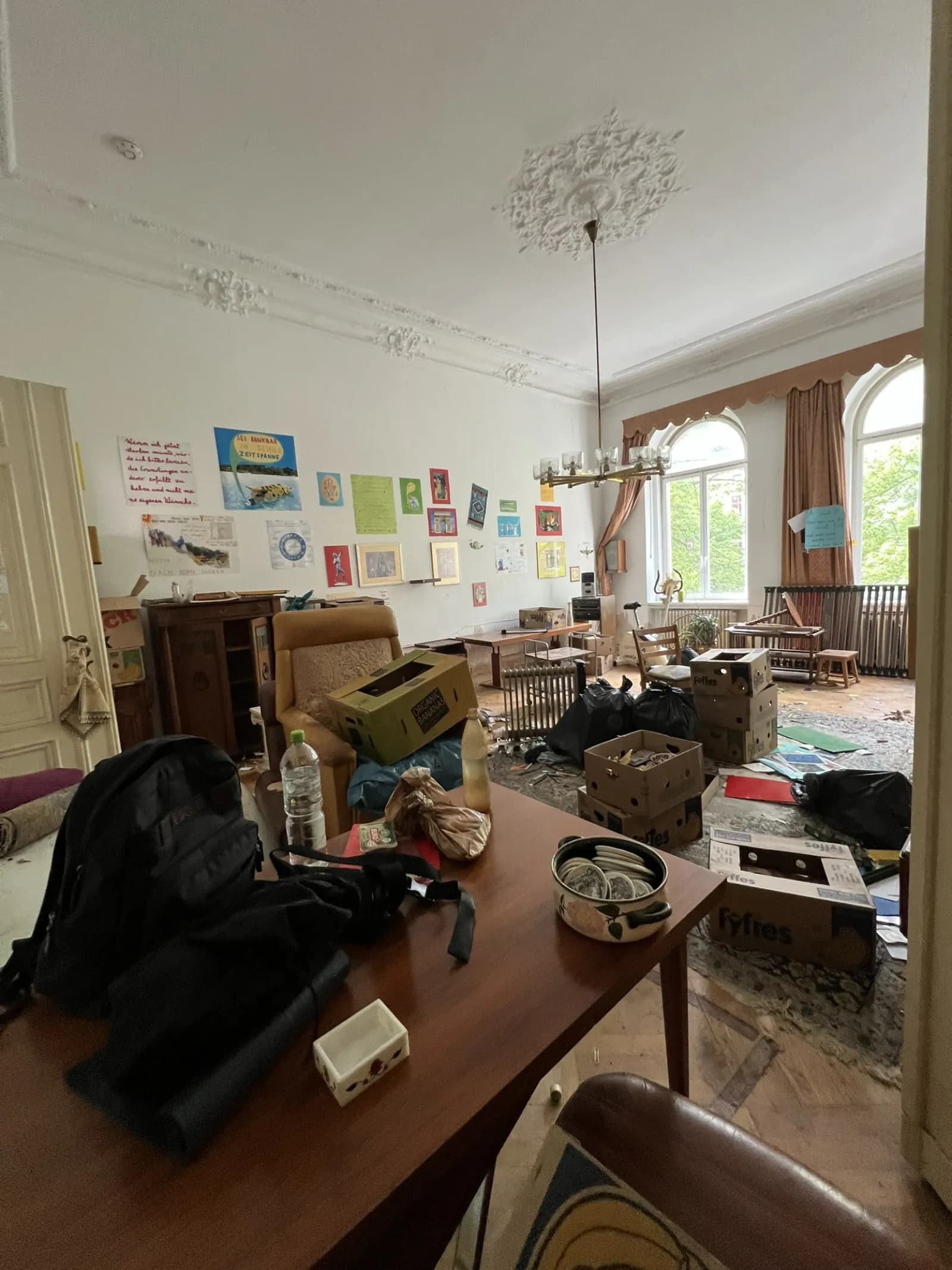 Cluttered living room with sofa, stacked boxes and household goods before the clearout
