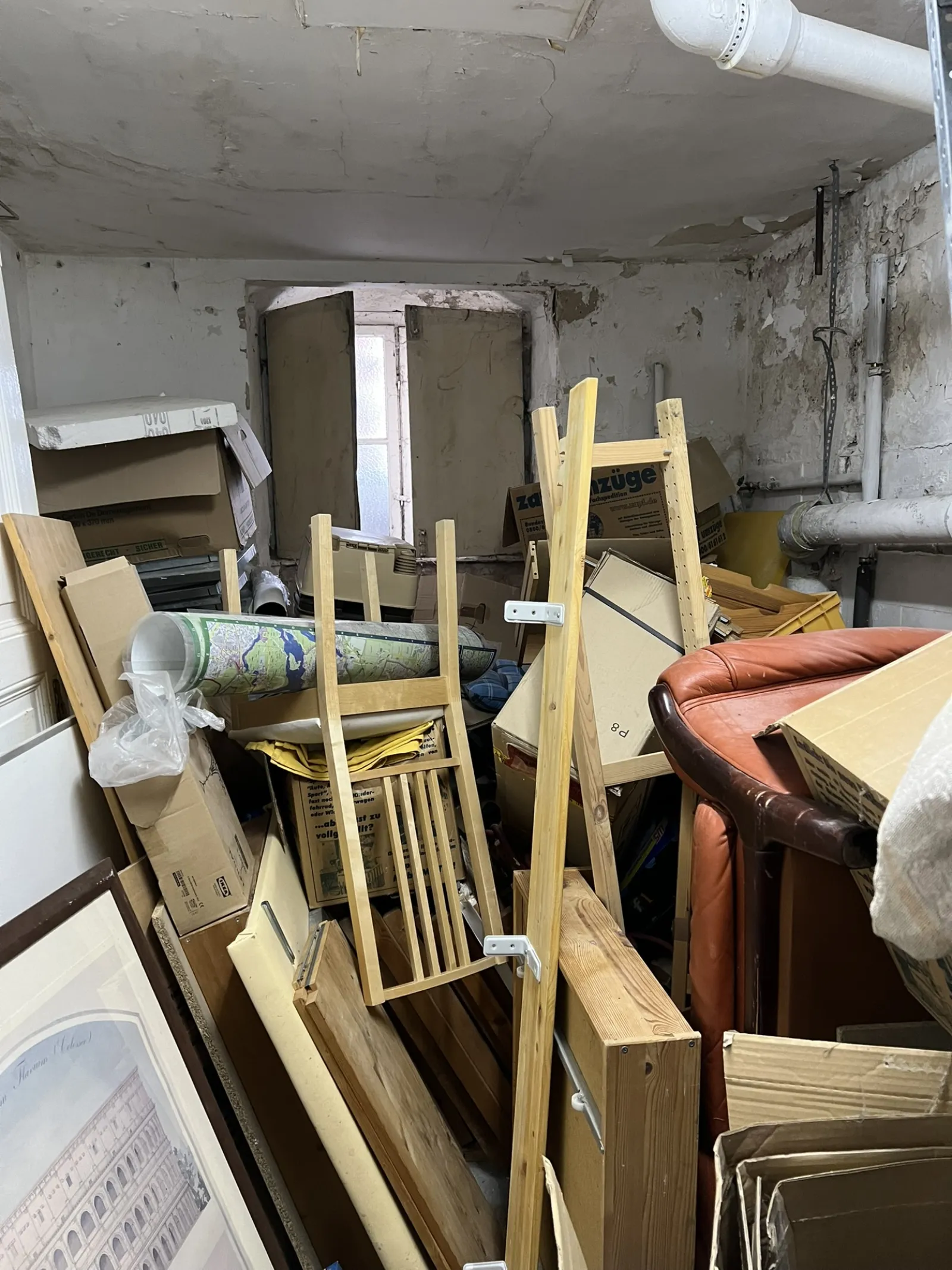 Cellar storage unit packed with wooden furniture, picture frames, rugs and boxes