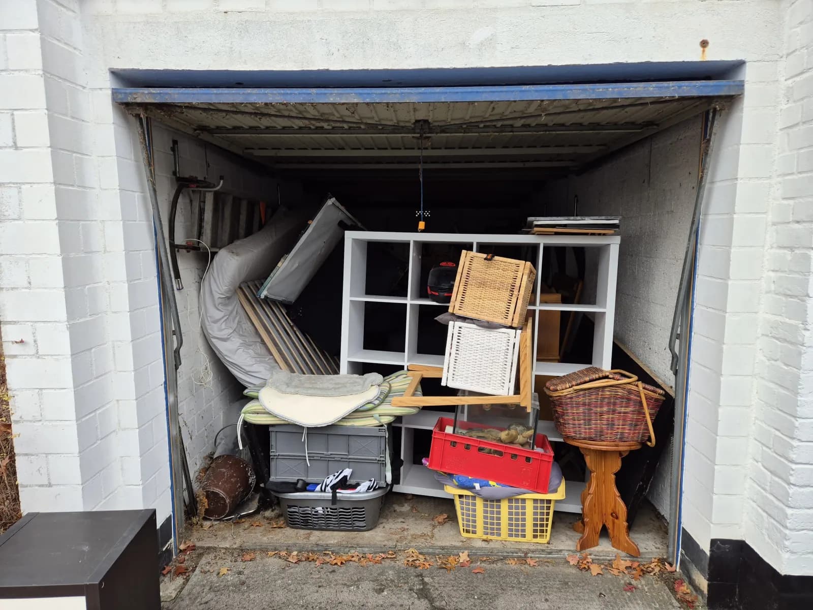 Open garage filled to the roof with furniture, baskets and household items