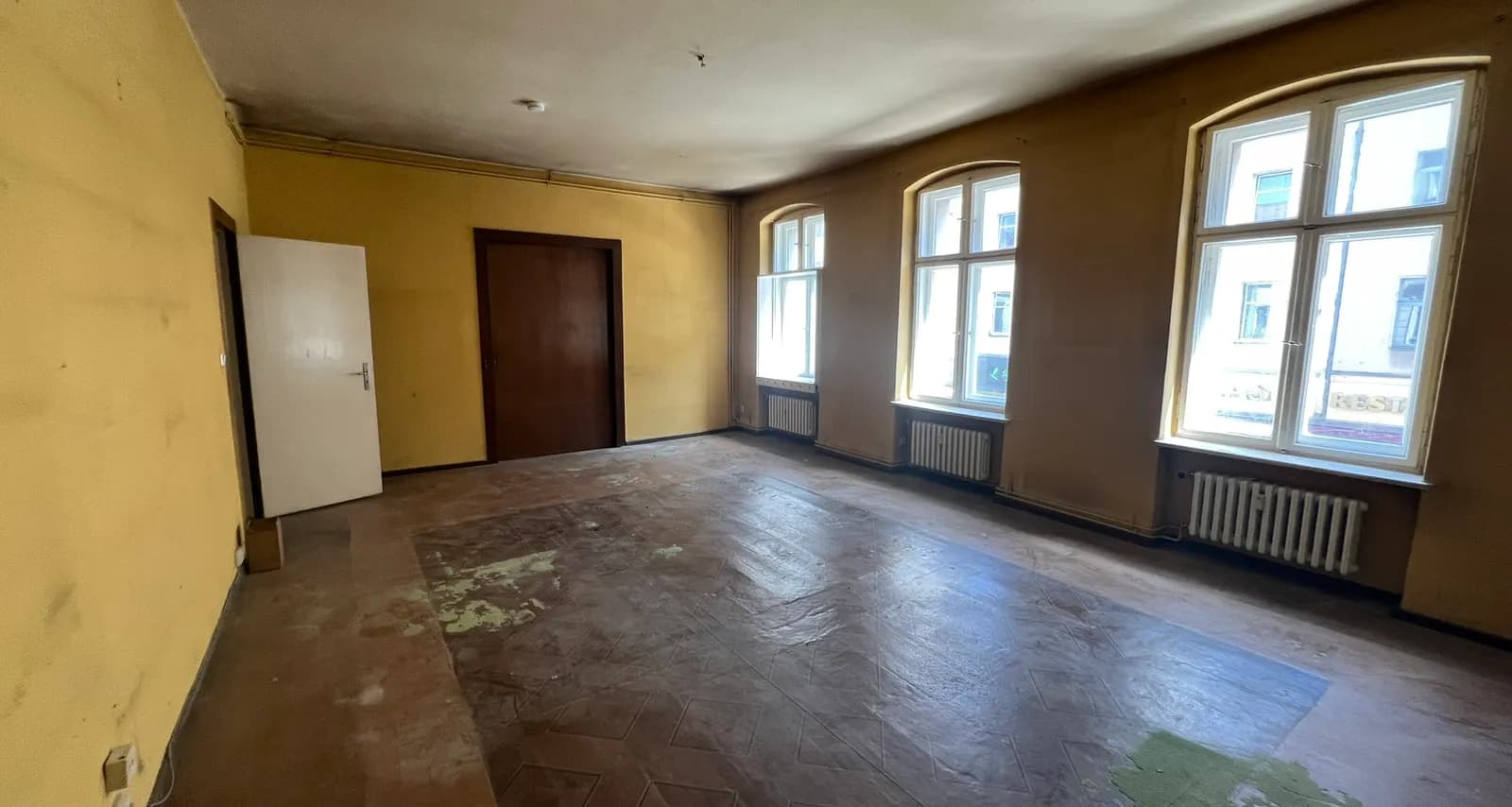 Fully cleared Berlin Altbau room with tall arched windows after a flat clearance and junk removal