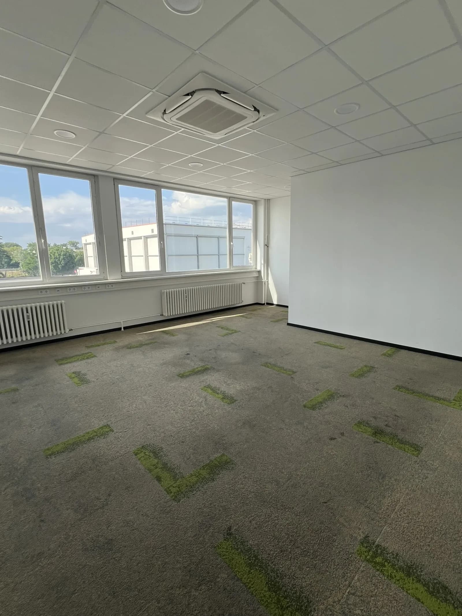 Leeres Bürozimmer mit Fliesenboden und großem Fenster nach abgeschlossener Gewerbeauflösung