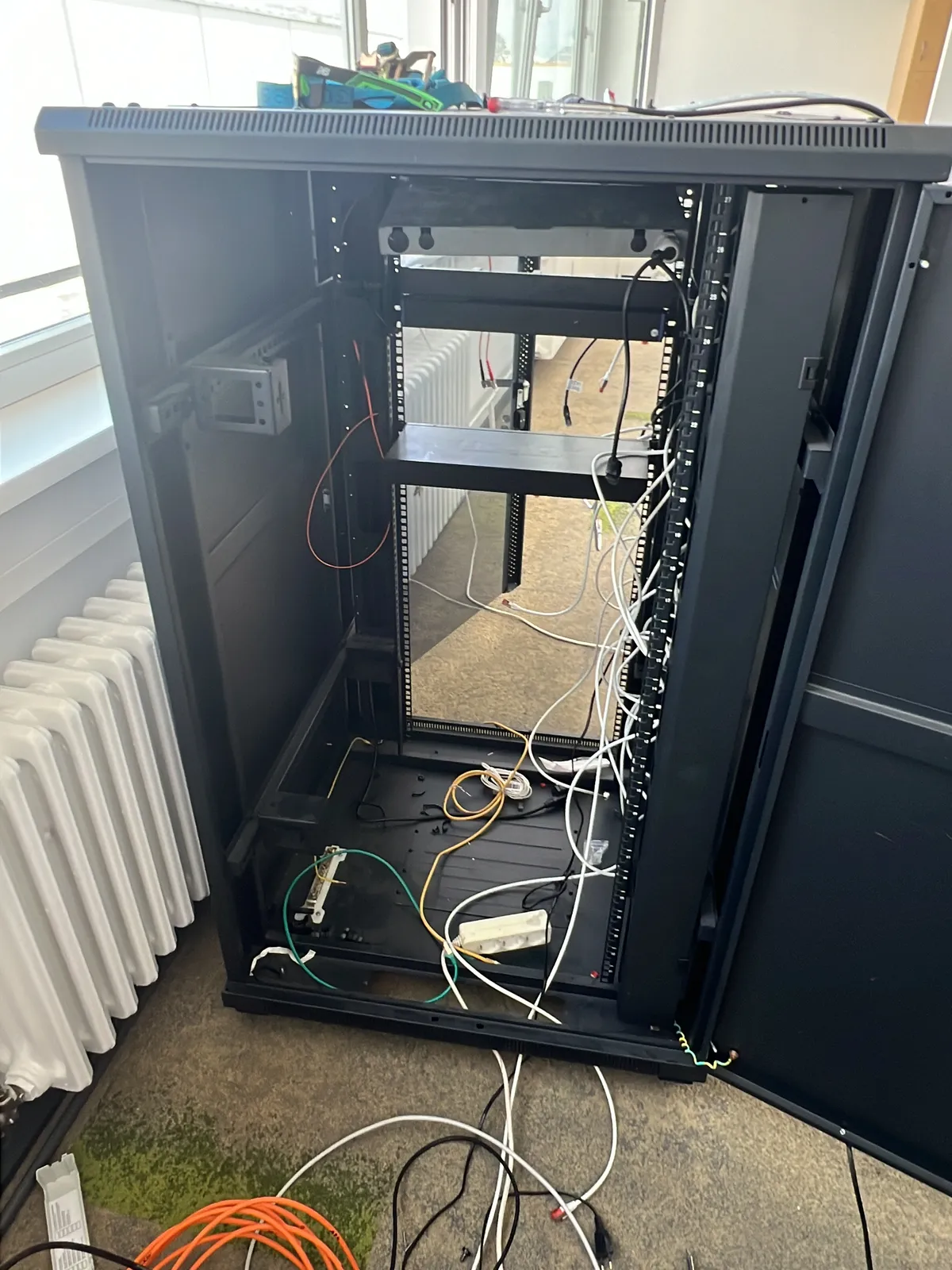 Demontage eines Serverschranks mit gelösten Netzwerkkabeln bei einer Gewerbeauflösung in Berlin, Akkuschrauber im Einsatz