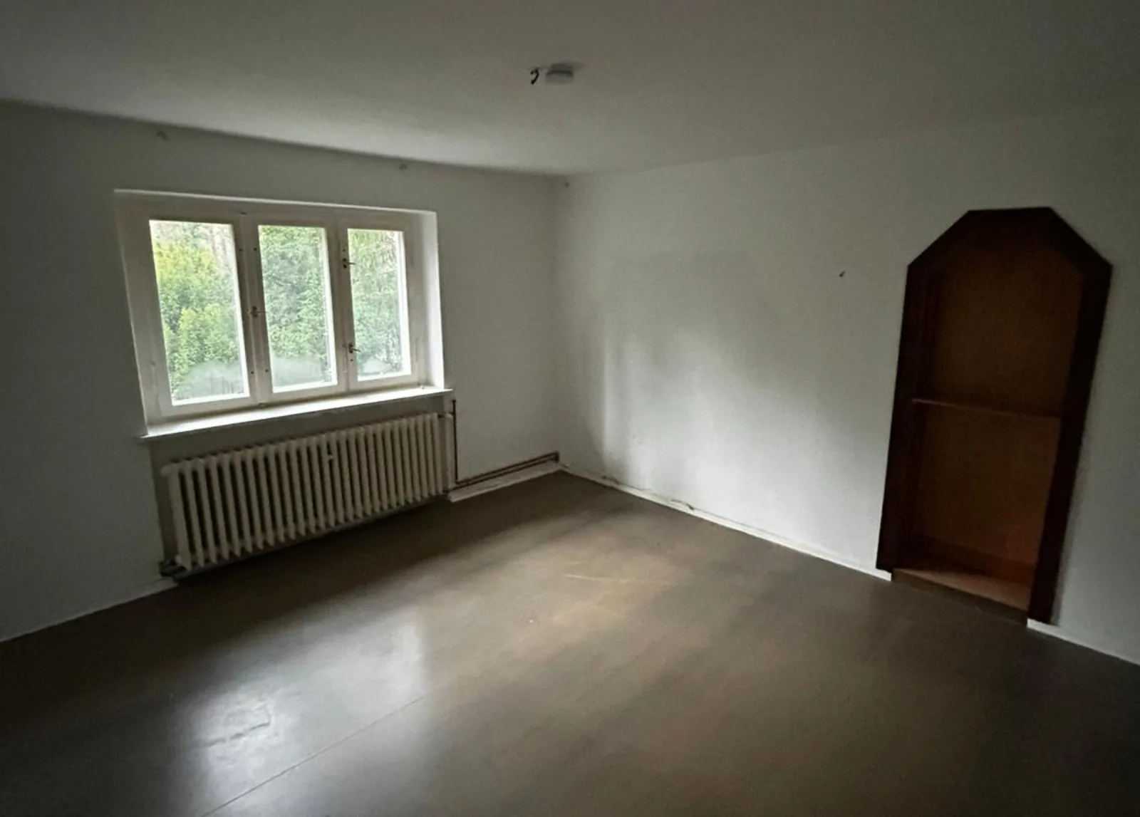 Leer geräumtes Zimmer einer Berliner Wohnung nach der Haushaltsauflösung, mit Fenster, Heizkörper und Eckschrank