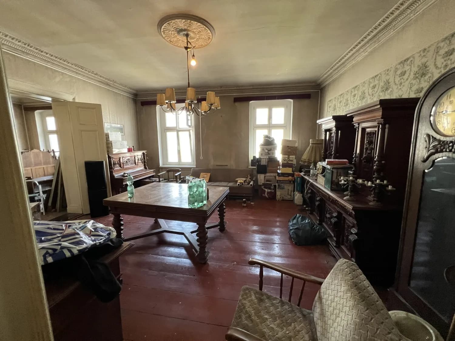 Vollständig möbliertes Altbau-Wohnzimmer in Berlin mit antikem Buffet, Standuhr und Klavier vor der Wohnungsauflösung im Todesfall