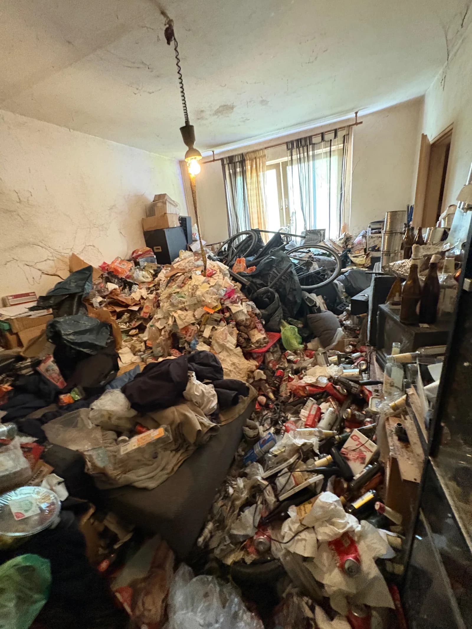 Bis unter die Decke vermülltes Wohnzimmer vor der Messie-Entrümpelung