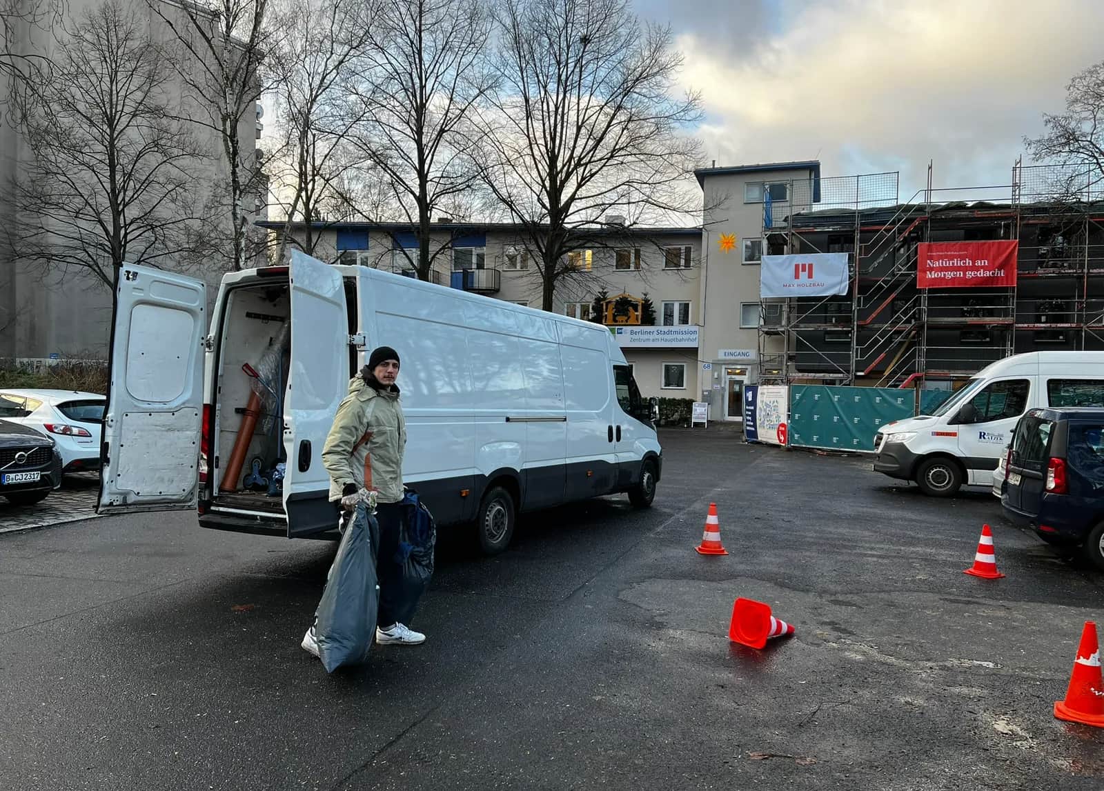 Alles4You-Mitarbeiter trägt einen Sack mit Spenden vom Transporter – Brauchbares wird in Berlin weitergegeben statt entsorgt