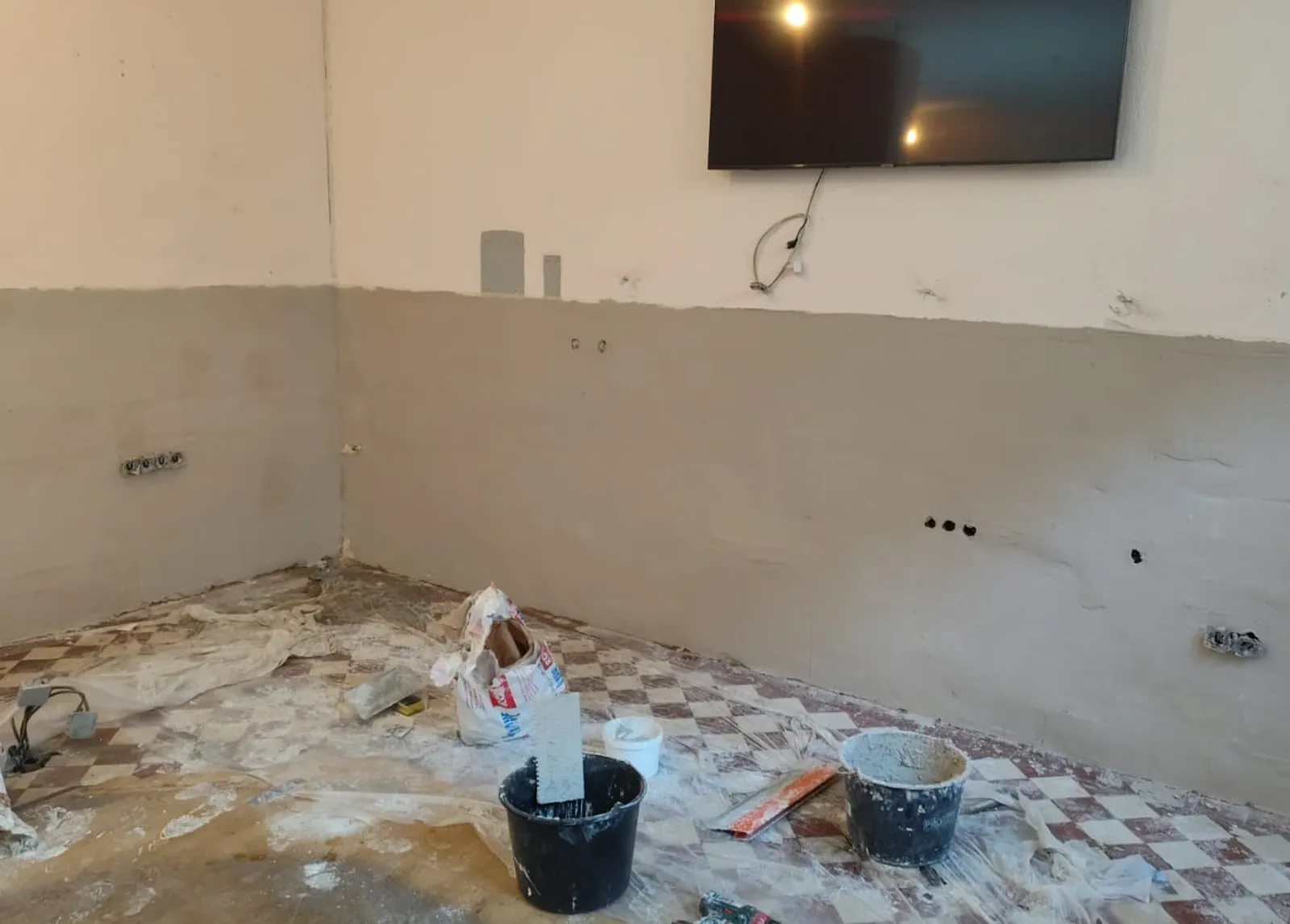 Renovierung in vollem Gange in einer Berliner Wohnung: frisch verputzte Wand, Eimer und Werkzeug bereit zum Verarbeiten