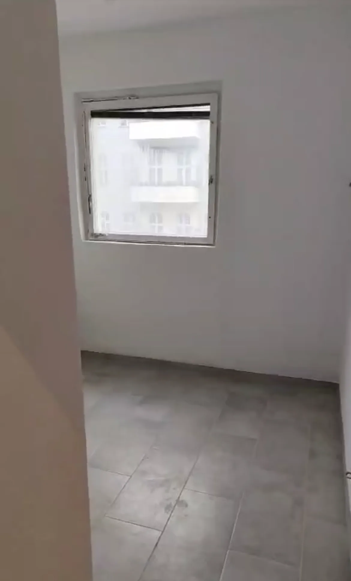 Fertig renovierter leerer Raum mit weißen Wänden und neuen grauen Bodenfliesen