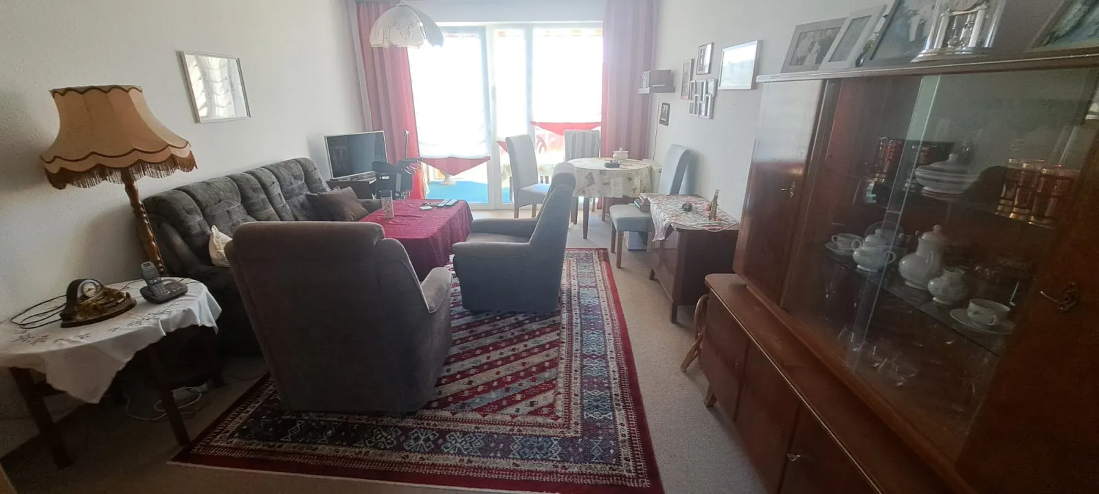 Vollmöbliertes Wohnzimmer mit Schrankwand, Sofa und Teppich vor dem Abtransport