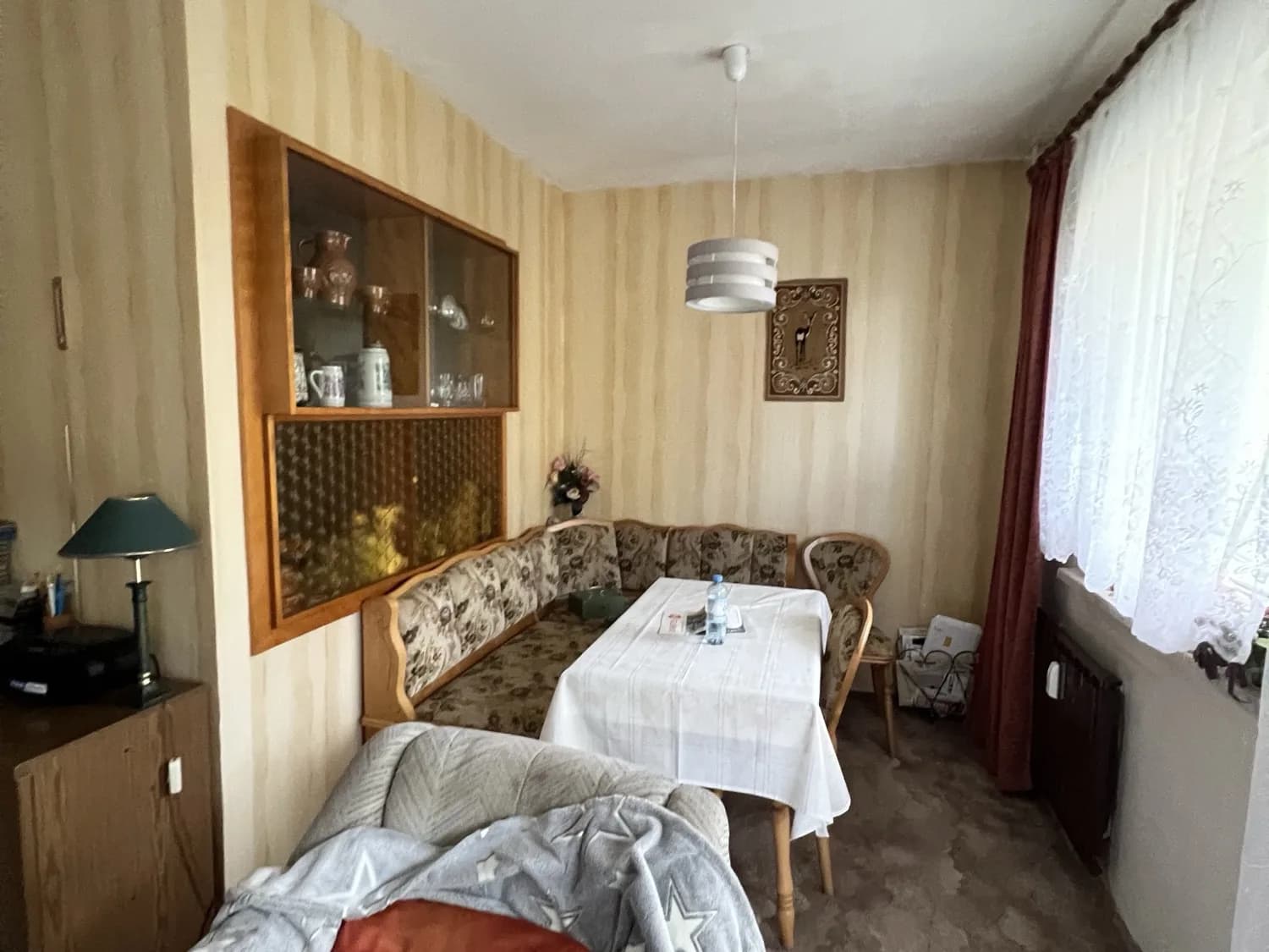Furnished living room of a Berlin flat with corner bench, dining table and wall unit before a flat clearance