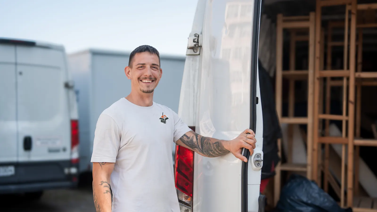 Mitarbeiter von Alles4You lächelt an der offenen Tür des Transporters