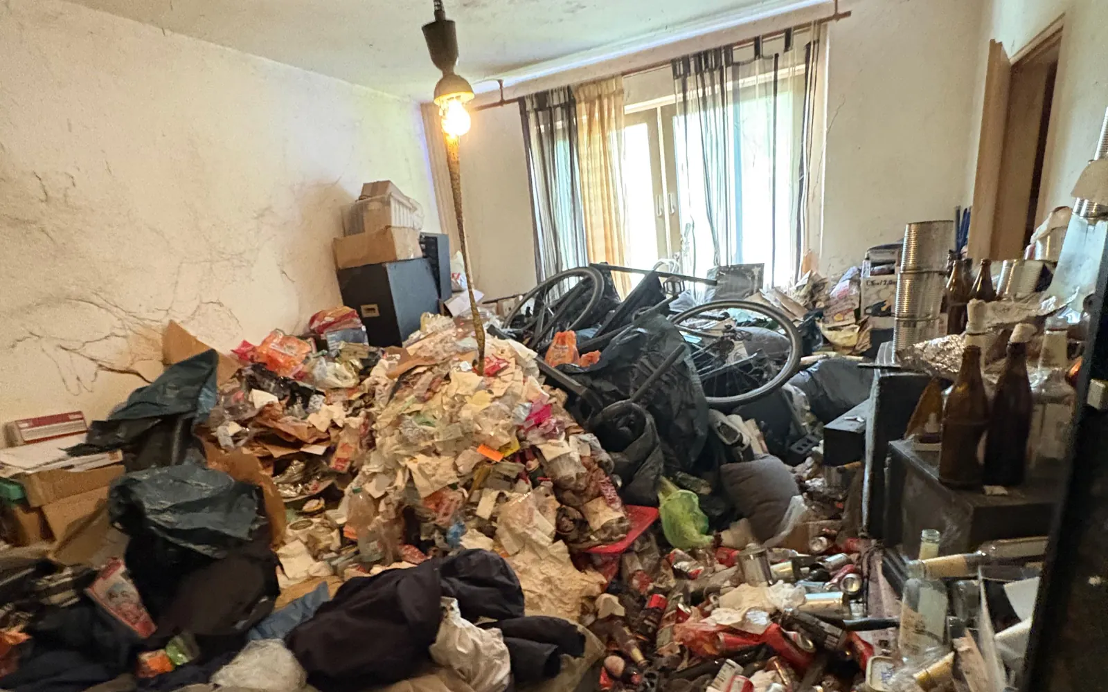 Stark vermülltes Zimmer einer Berliner Messie-Wohnung mit meterhohem Müllberg, Fahrrad und Kisten vor der Entrümpelung