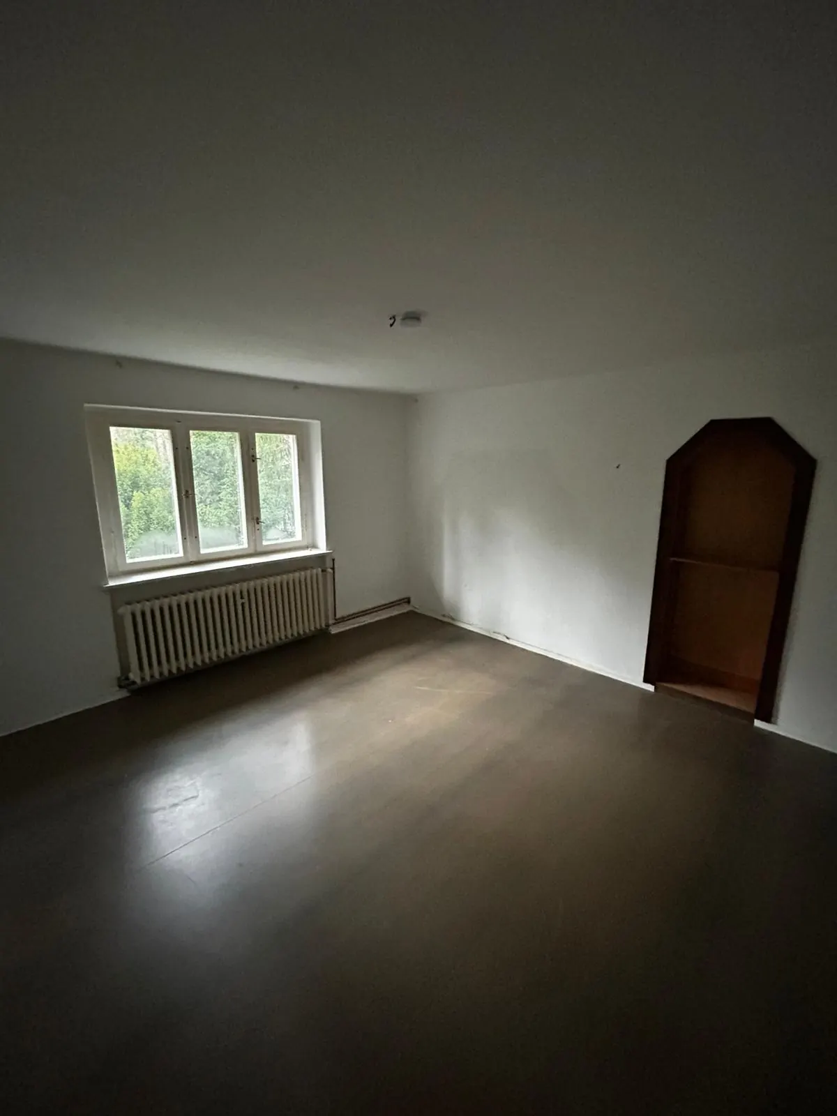 Leer geräumtes, besenreines Zimmer einer Berliner Wohnung mit Fenster, Heizkörper und Eckschrank