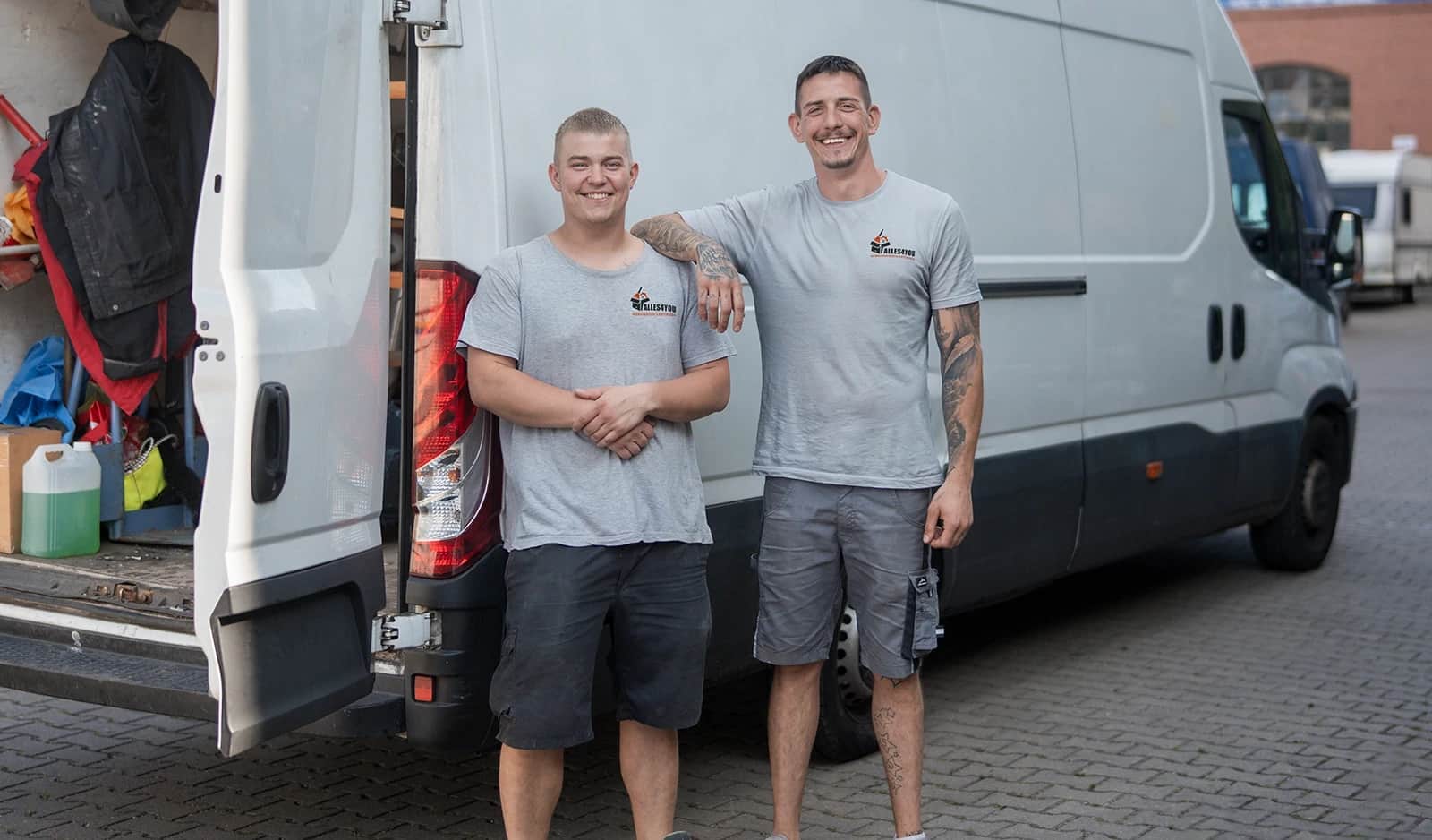 Zwei festangestellte Mitarbeiter von Alles4You am Transporter vor einer Entrümpelung