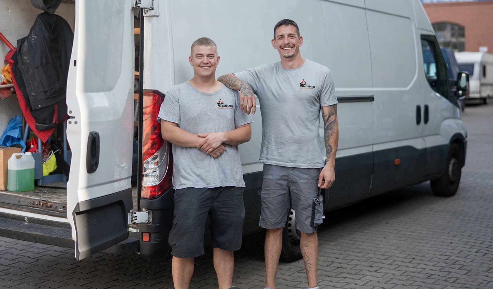 Zwei Alles4You-Mitarbeiter in Firmen-Shirts vor ihrem weißen Transporter in Berlin